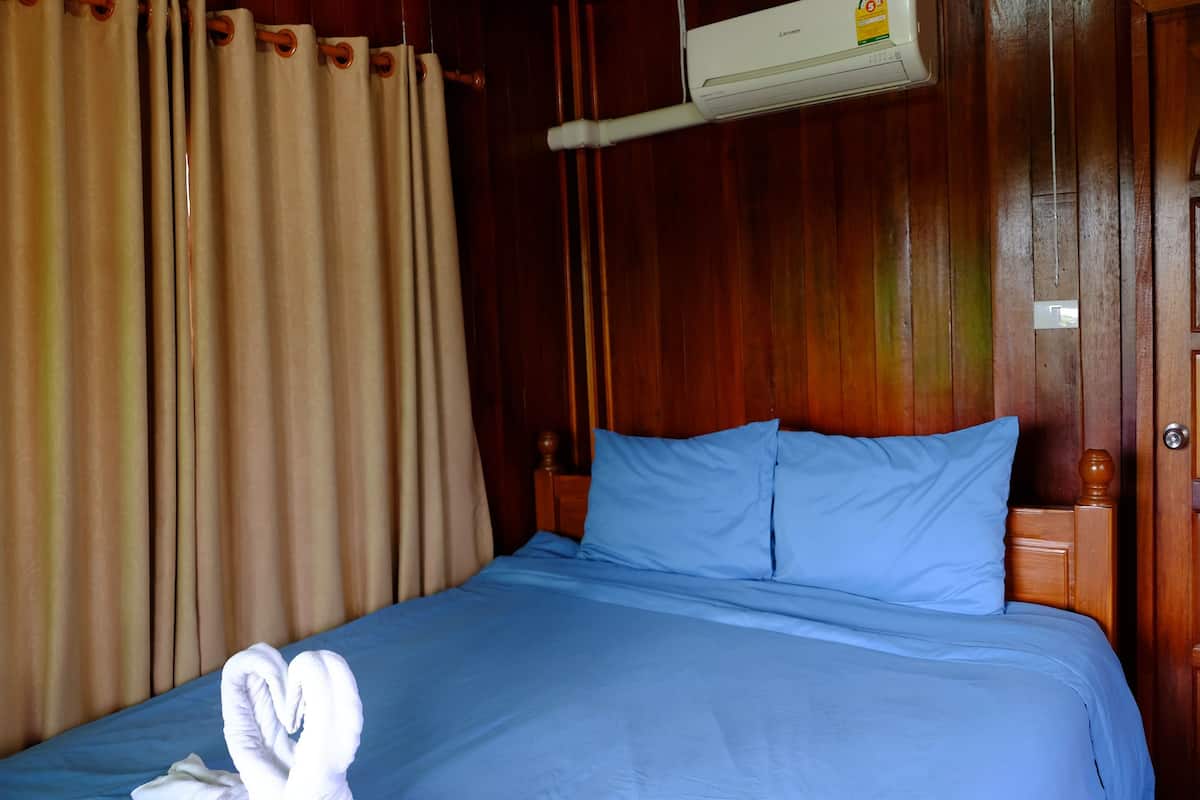 Ein Hotelzimmer mit Holz-Kopfteil, einem Bett mit blauer Bettwäsche und einem bettwäschegefalteten Schwan.