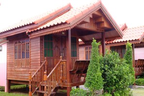 A traditional wooden house with a tiled roof, a wooden staircase, and a small garden area. - Banmai Hom Resort (Pluak Daeng)