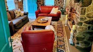 Un salon chaleureux avec un mur en pierre, une cheminée et un lustre.