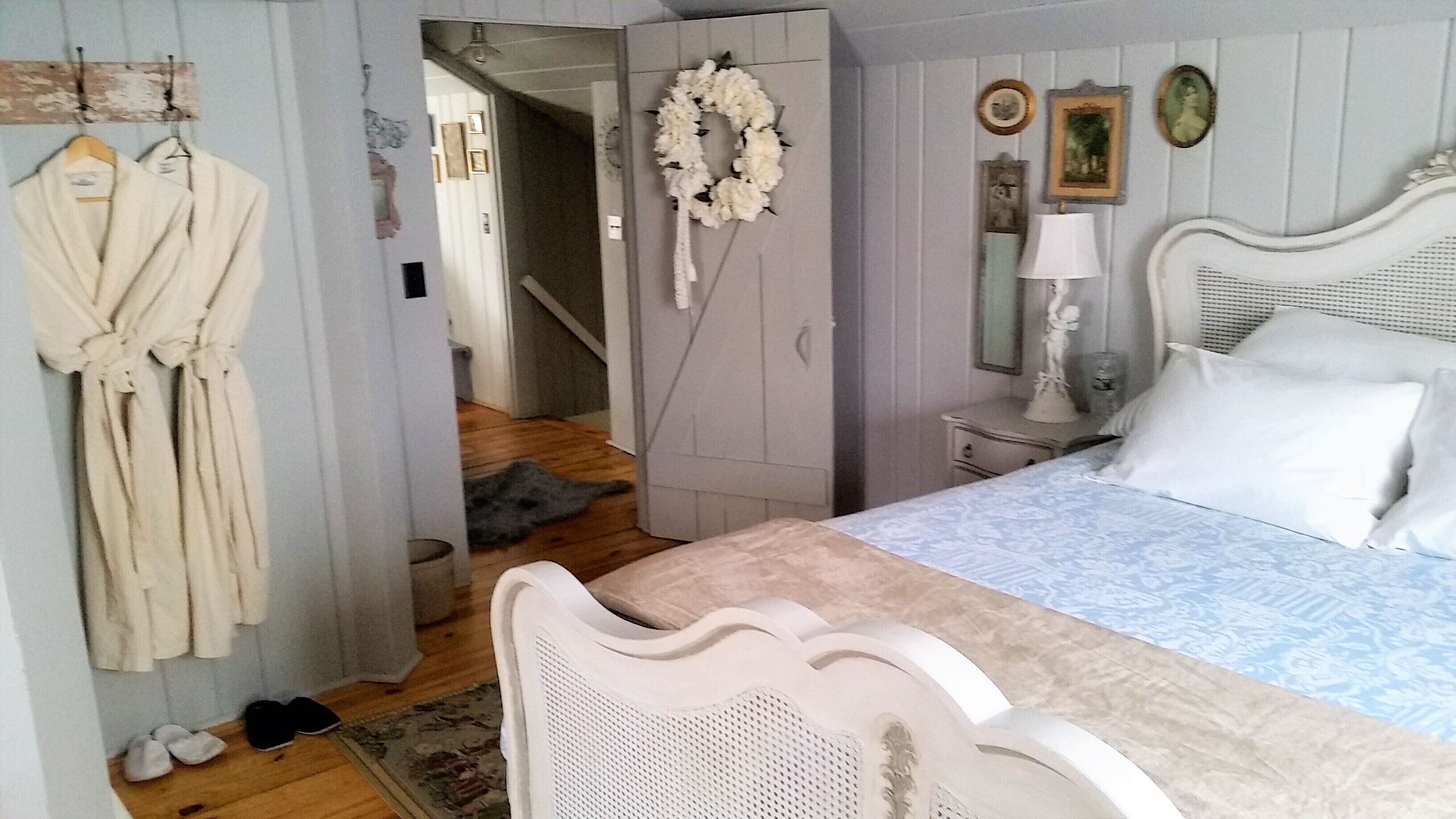A bedroom with a bed, a nightstand, a mirror, and a wardrobe.