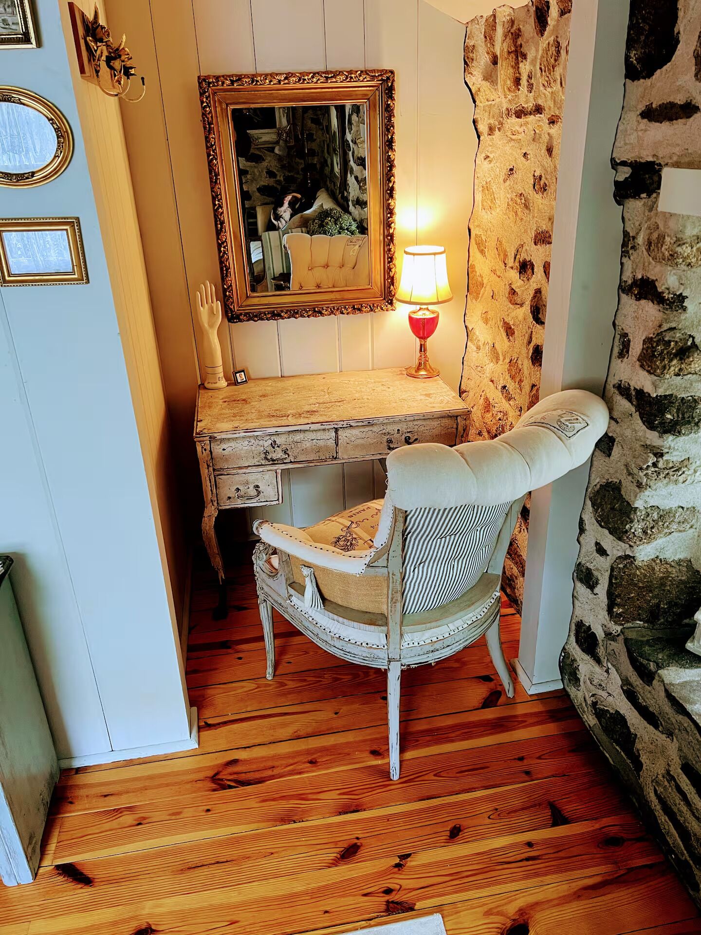 A rustic room with a wooden desk, a chair, a mirror, and a lamp.