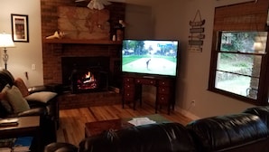 Una sala de estar con chimenea, televisor y ventana.