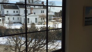 A room with a large window overlooking a residential area with houses and bare trees.
