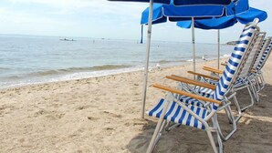 A beach with rows of striped beach chairs and blue umbrellas.