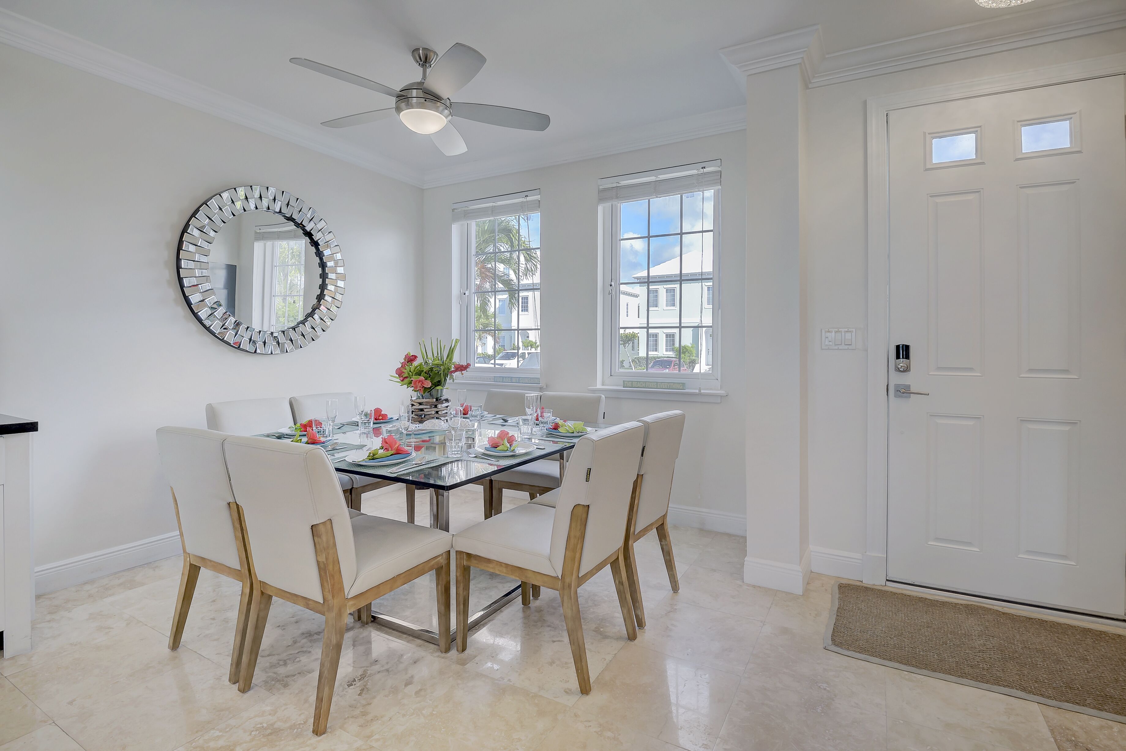 A dining area with a round table, chairs, and a ceiling fan.