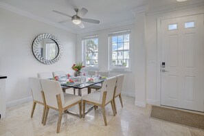 A dining area with a round table, chairs, and a ceiling fan.