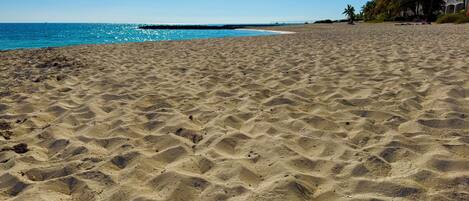 A sandy beach with a clear blue sky and calm sea.