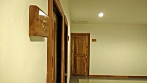 Un couloir avec une porte en bois et une pancarte accrochée au mur.