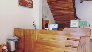 Un comptoir d’accueil en bois, avec une enseigne au-dessus, une bouilloire et une petite table sur laquelle se trouve un récipient.