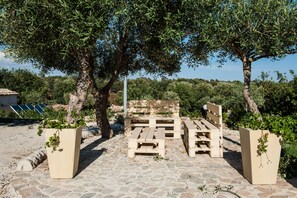 Un espacio al aire libre con pavimento de piedra, bancos de madera y jardineras.