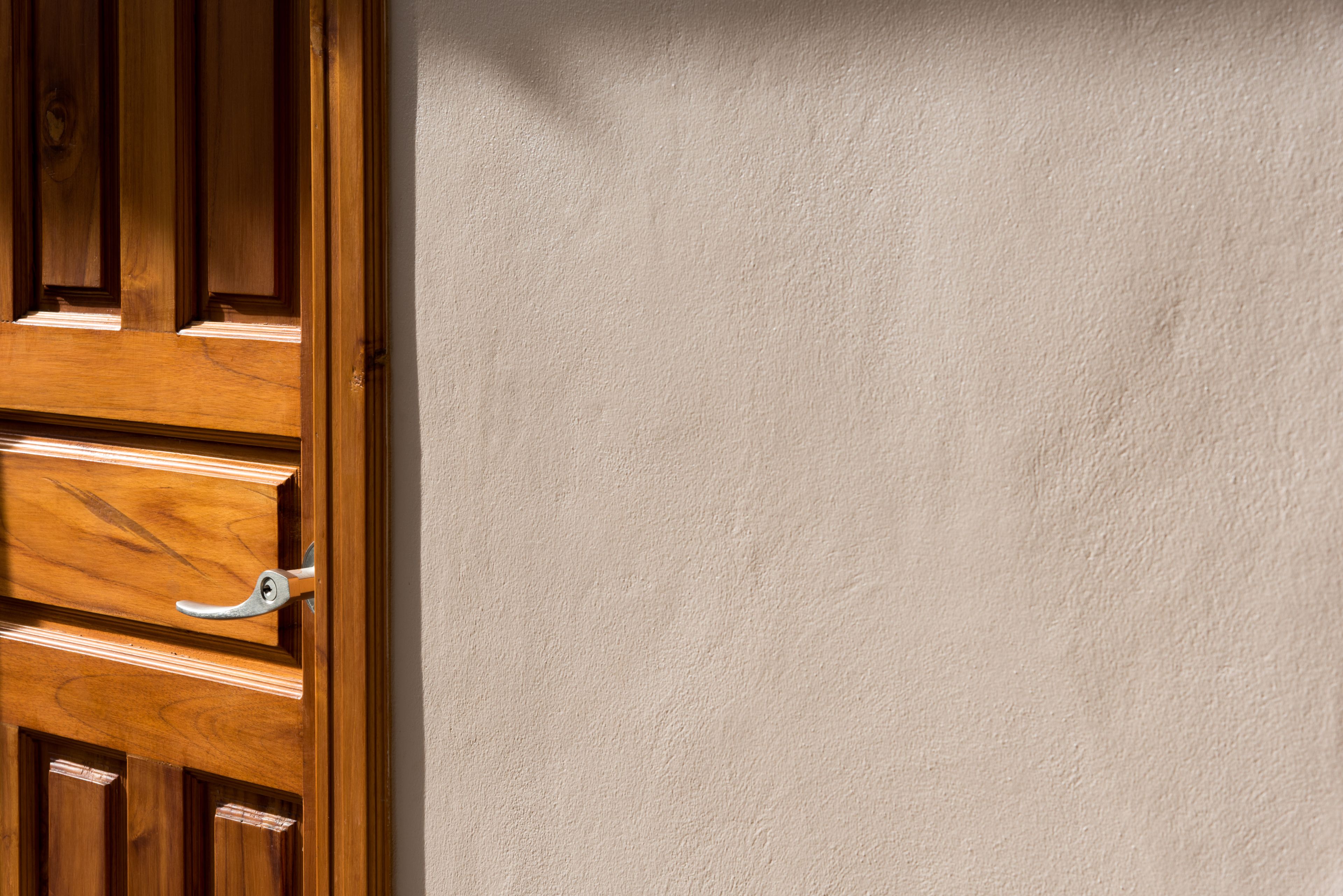 Une porte en bois avec une poignée et un mur à la texture particulière.