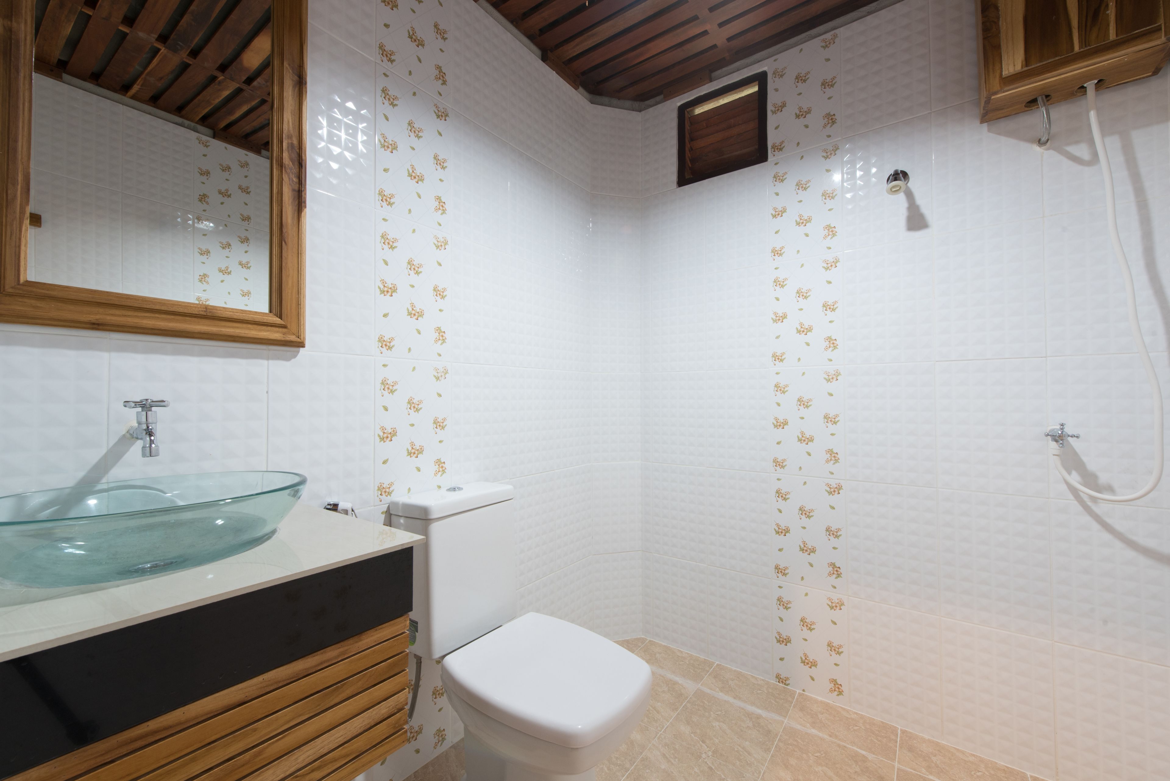 A bathroom with a glass sink, white toilet, and shower.