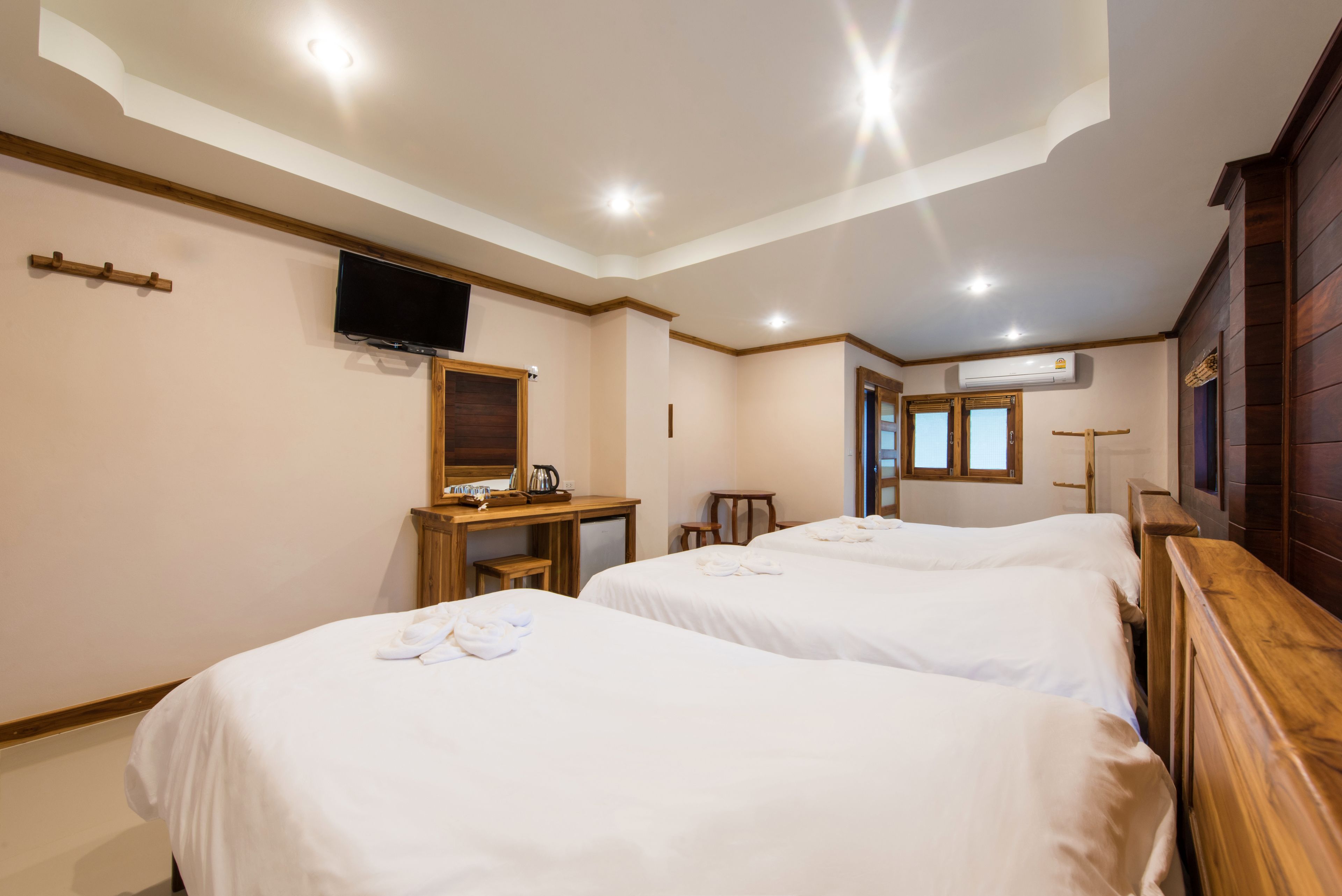 Habitación de hotel con dos camas, un escritorio, un televisor y aire acondicionado.