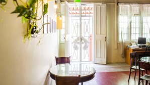 A room with a round glass table, wooden chairs, a green pendant light, and a white door with decorative glass panels. - Homeaway Townhouse 1934 (George Town)