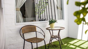 A small patio with a wicker chair, a round table, and a potted plant. - Homeaway Townhouse 1934 (George Town)