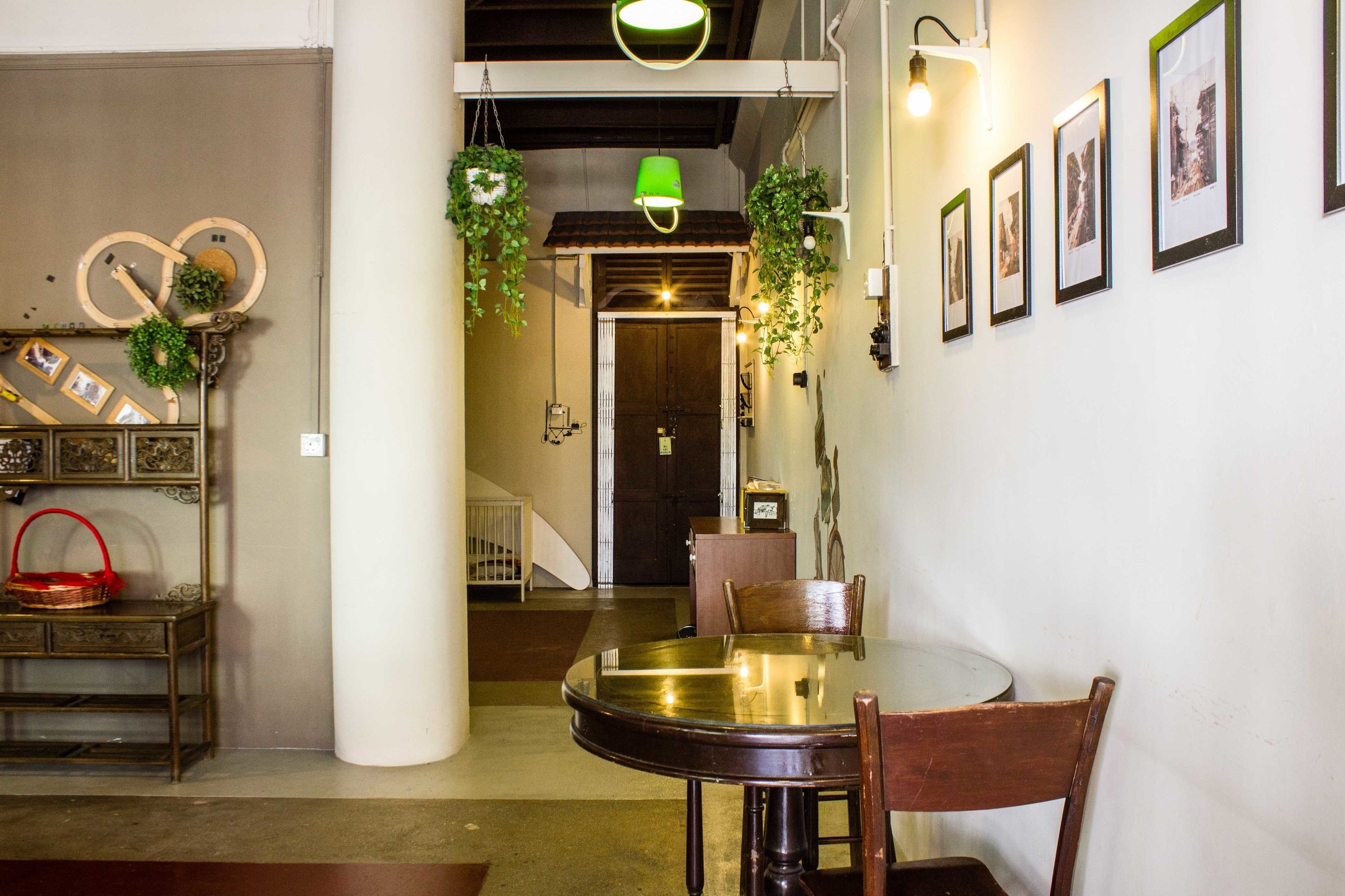 Un comedor con una mesa redonda, sillas y plantas colgantes. Una escalera conduce a otra habitación.