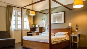 A four-poster bed with a wooden frame, a bedside table, a nightstand, a chair, and a map on the wall. - Homeaway Townhouse 1934 (George Town)