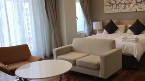 Une chambre d’hôtel avec un lit, deux canapés, une table ronde et un tableau au mur.