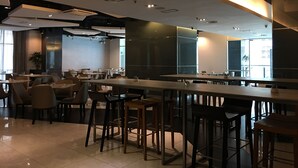 Un restaurant moderne avec des tables et des chaises hautes, de grandes fenêtres et un design épuré et minimaliste.