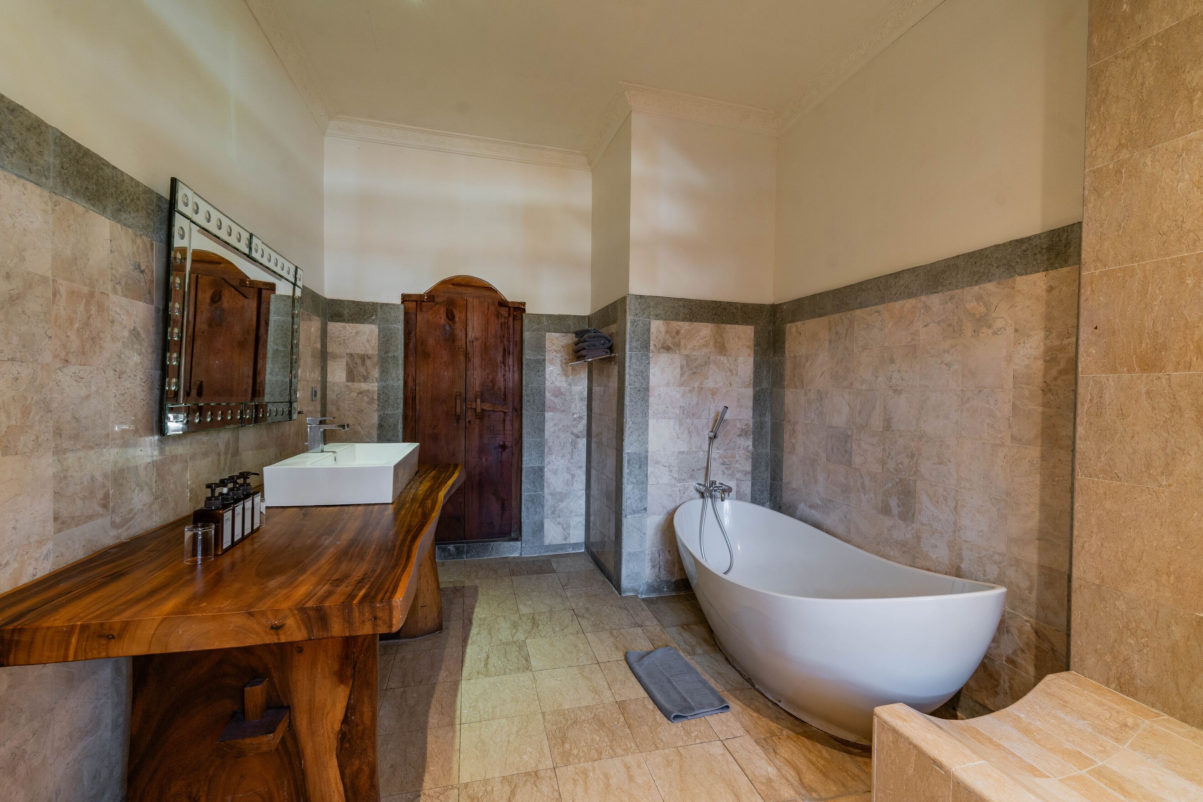 Une salle de bain avec un meuble-lavabo en bois, une grande baignoire et un espace douche.