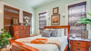 Un dormitorio con una cama de madera, una mesita de noche, un aparador y una planta en maceta.