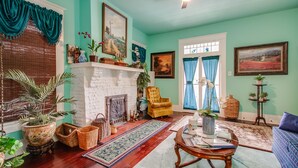 Una sala de estar con chimenea, un sillón amarillo y diversas plantas.