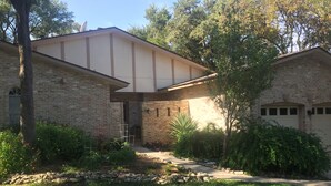 A two-story house with a brick exterior, a covered entryway, and a stone pathway leading to the front door.