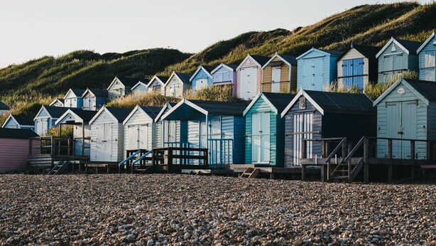 A row of beach huts with a pebble beach in the foreground and a hill in the background. - Beautiful 3 bed cottage in Lymington. Perfectly located for Coast and New Forest (Lymington)