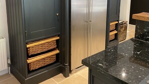 A kitchen with dark cabinetry, stainless steel appliances, and a marble countertop. - Beautiful 3 bed cottage in Lymington. Perfectly located for Coast and New Forest (Lymington)