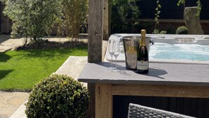 A hot tub with a bottle of champagne and glasses on a wooden table. - Beautiful 3 bed cottage in Lymington. Perfectly located for Coast and New Forest (Lymington)
