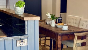 A kitchen with a built-in stove, a dining table with chairs, and a potted plant on the counter. - Beautiful 3 bed cottage in Lymington. Perfectly located for Coast and New Forest (Lymington)