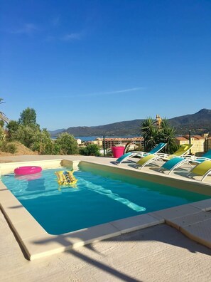 A swimming pool with lounge chairs, a pink inflatable ring, and a yellow float. - Awesome residence with a pool and a great view (Propriano)