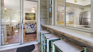 A kitchen with a countertop, a bench, and a door leading to a dining area.