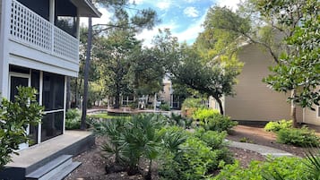 Enjoy a serene garden oasis with a two-story house and balcony overlooking lush greenery and a tranquil fountain.