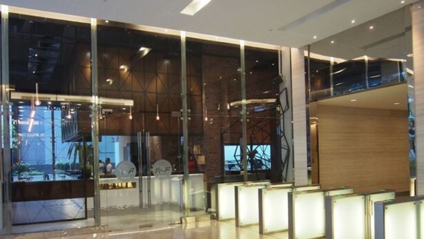 A modern lobby with glass partitions, a reception desk, and a view of the outside. - WTE Binjai 8 Suites (Kuala Lumpur)