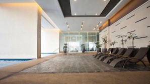A modern indoor pool area with lounge chairs and potted plants. - WTE Binjai 8 Suites (Kuala Lumpur)