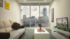 A modern living room with a large window, a sofa, a coffee table, and a flat-screen TV. - WTE Binjai 8 Suites (Kuala Lumpur)