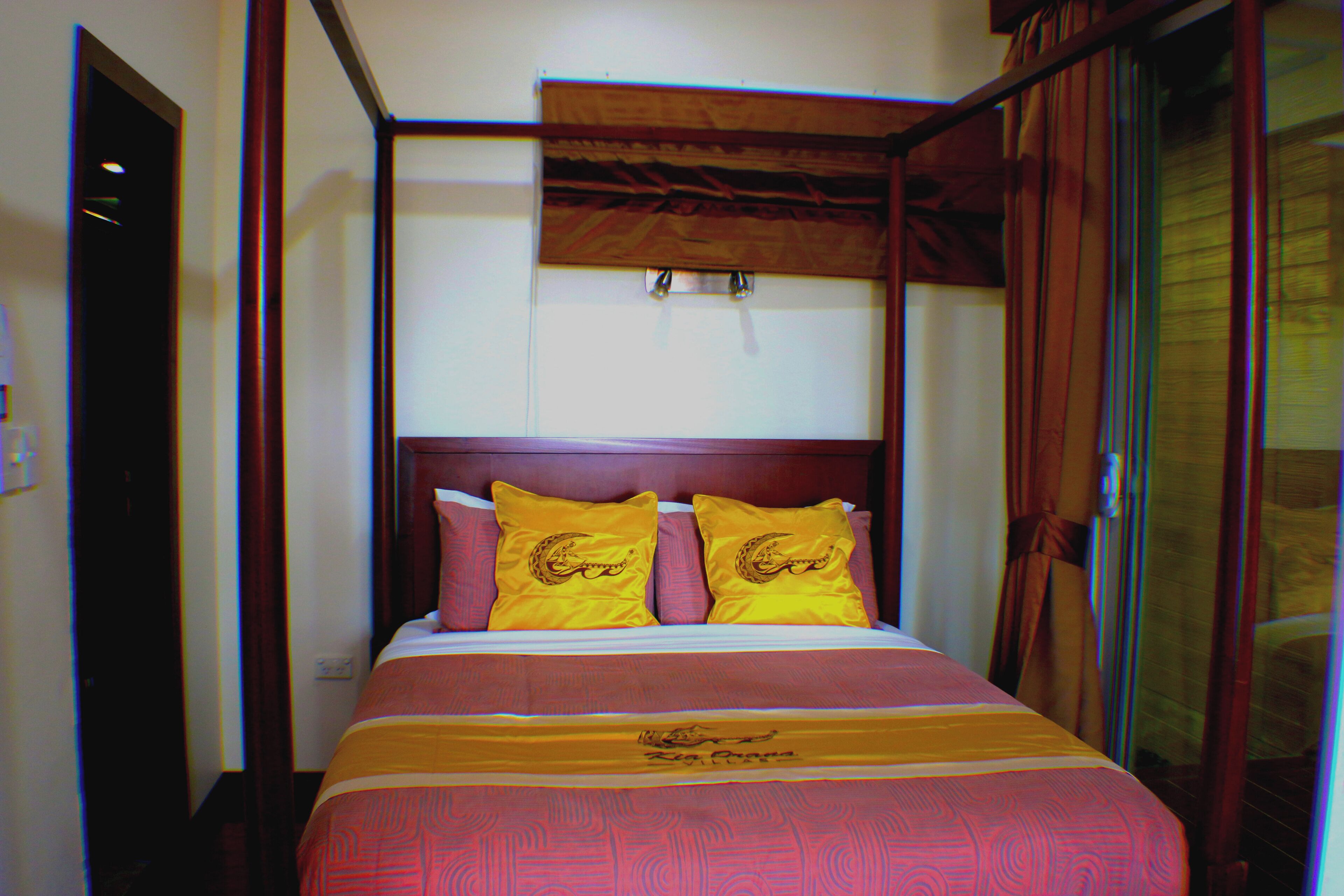 A bed with a wooden headboard, two pillows with a lion design, and a bedspread with a pattern.