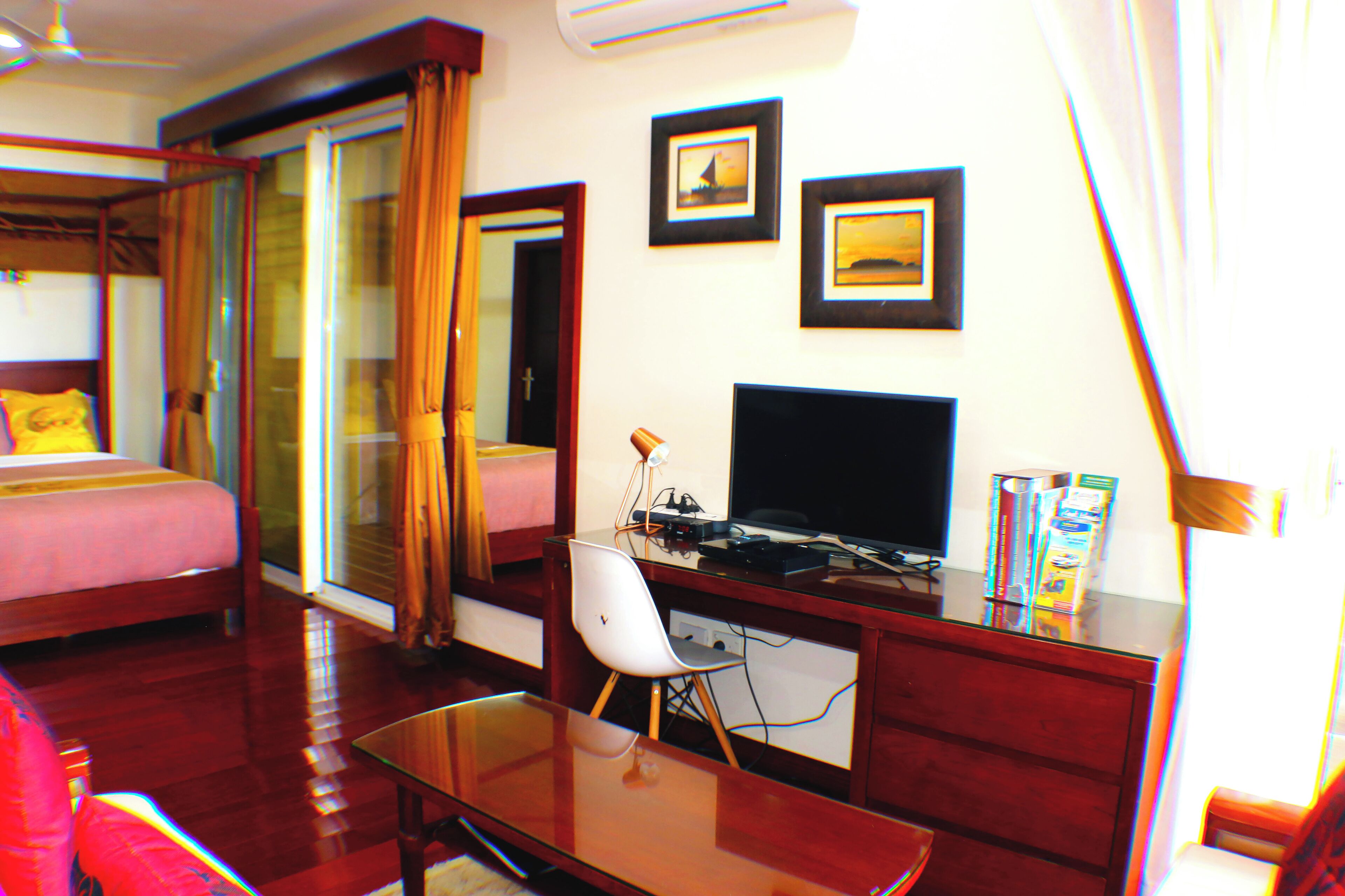 Une chambre d’hôtel avec un lit, un bureau équipé d’un ordinateur, une chaise et un téléviseur. Il y a des rideaux et une fenêtre.