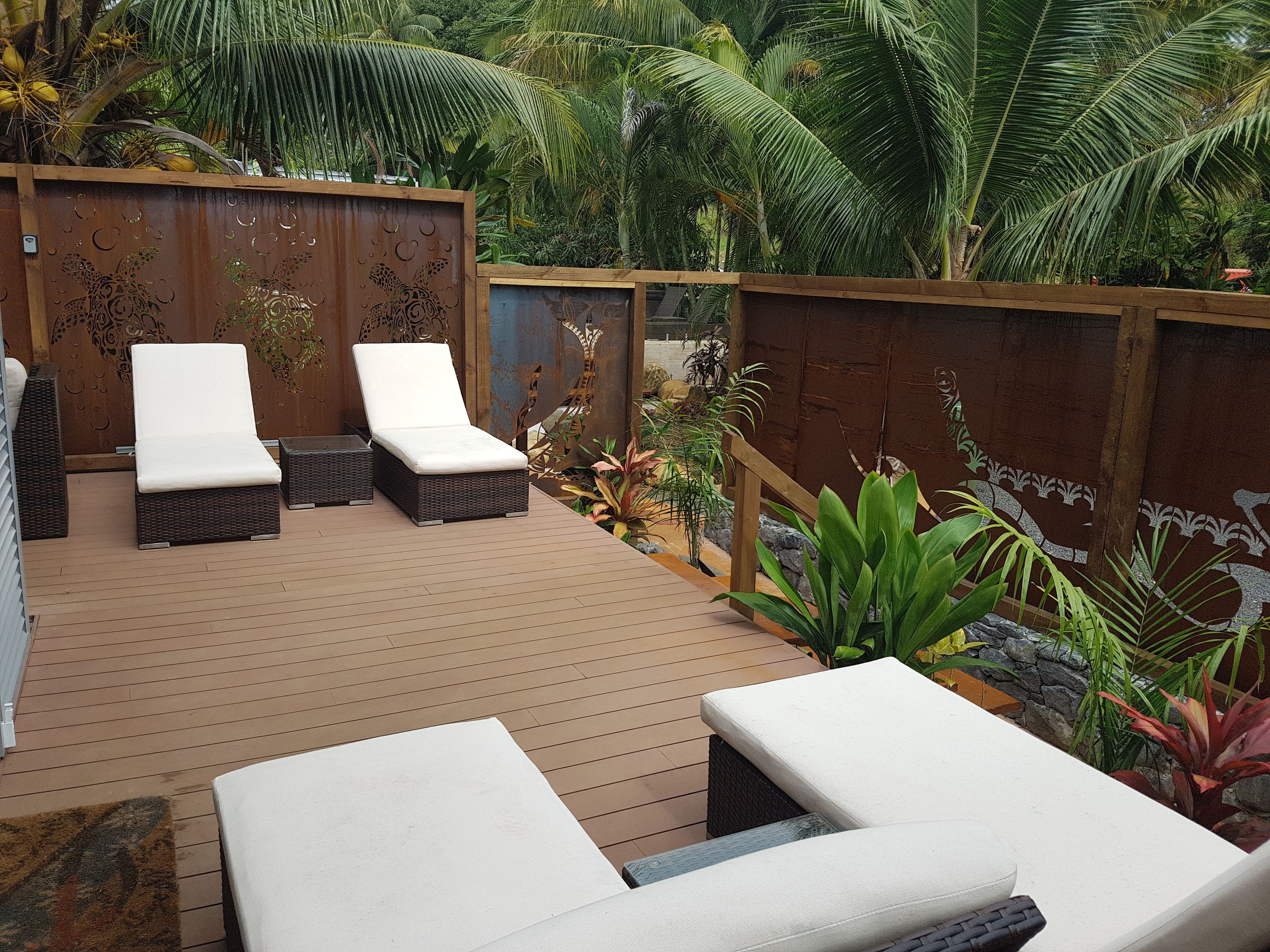 Una terraza de madera con dos sillas reclinables y una mesita.