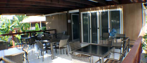 Eine Terrasse im Freien mit Korbmöbeln und einer Glastür zu einem überdachten Bereich.