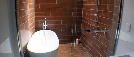 A bathroom with a freestanding bathtub, a shower, and a toilet.