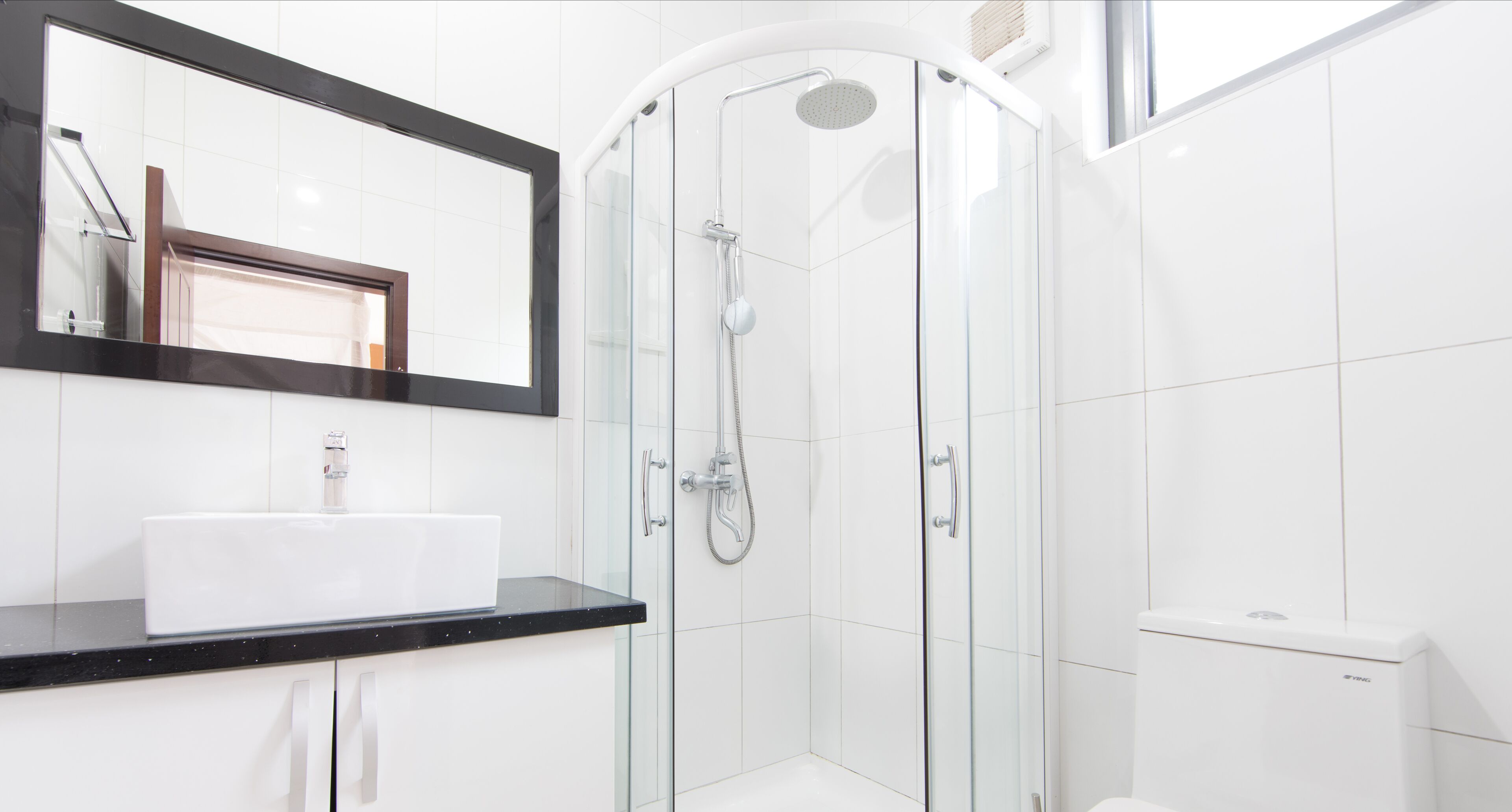 Une salle de bain moderne avec une douche à parois de verre, un lavabo blanc et des toilettes.