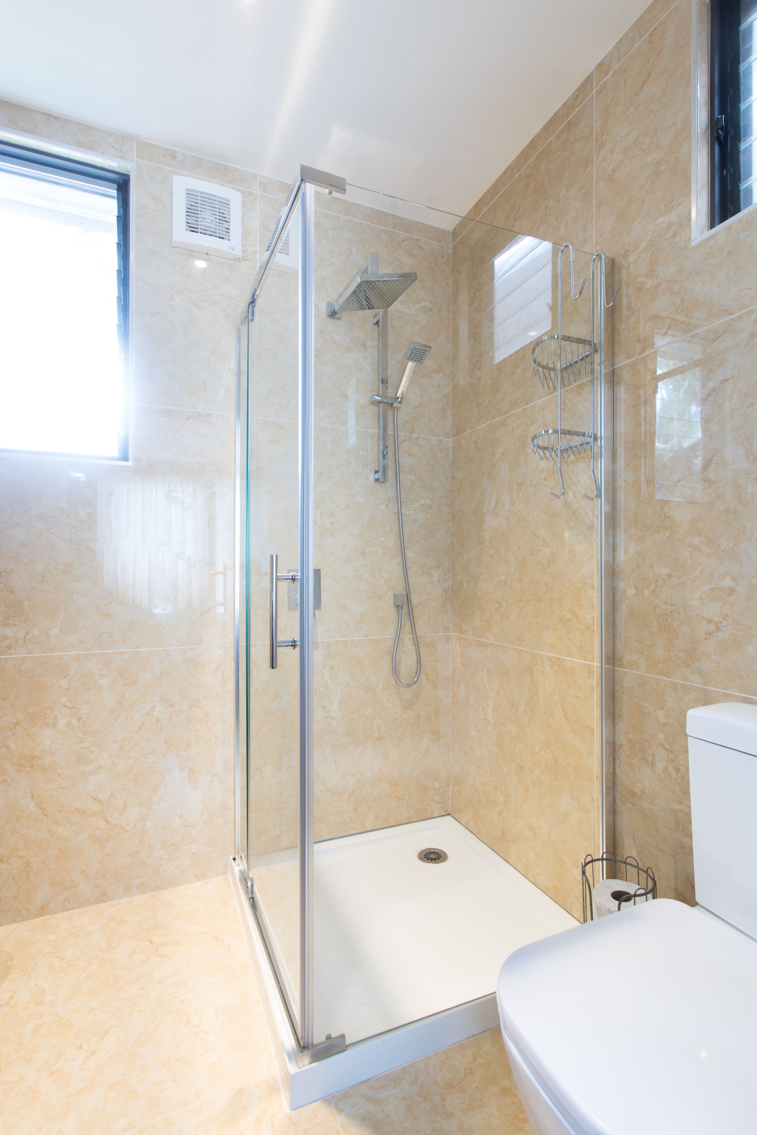 Un baño moderno con ducha envuelta en vidrio, inodoro y lavamanos.