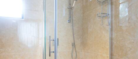 Un baño moderno con ducha envuelta en vidrio, inodoro y lavamanos.