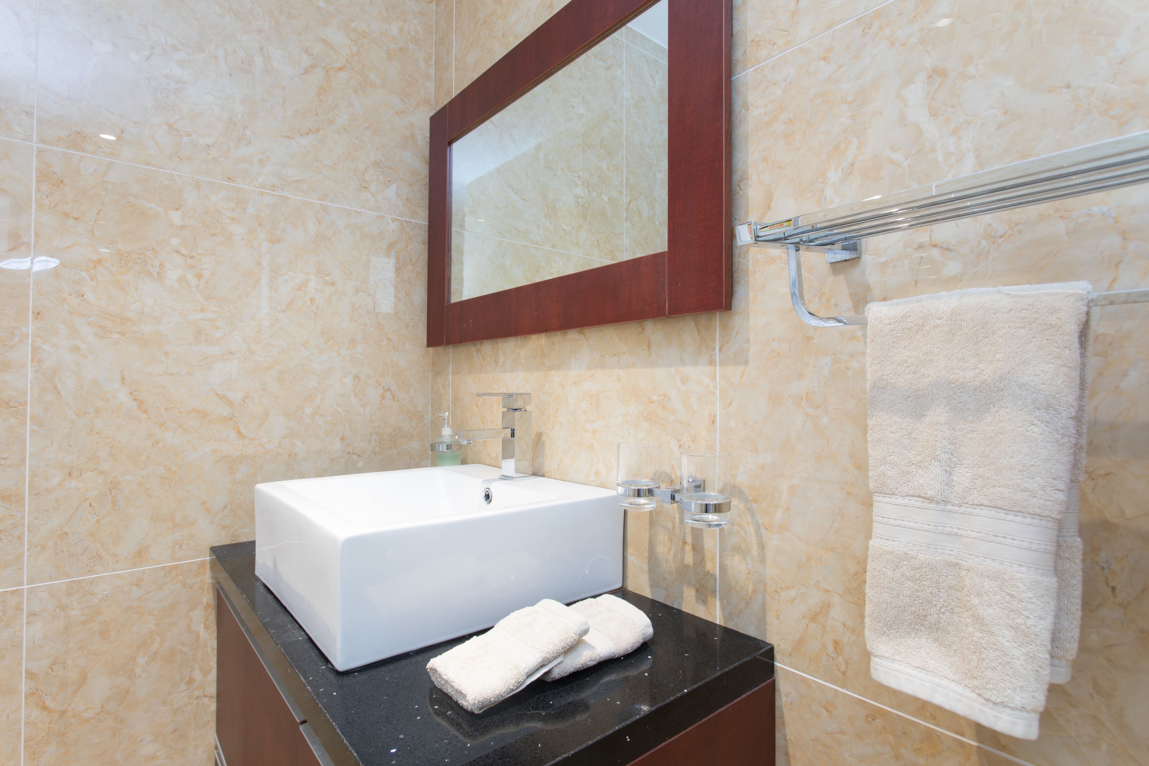 A bathroom with a white sink, a mirror, and a towel rack.