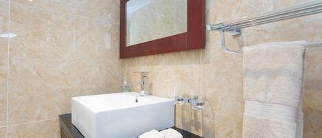 A bathroom with a white sink, a mirror, and a towel rack.