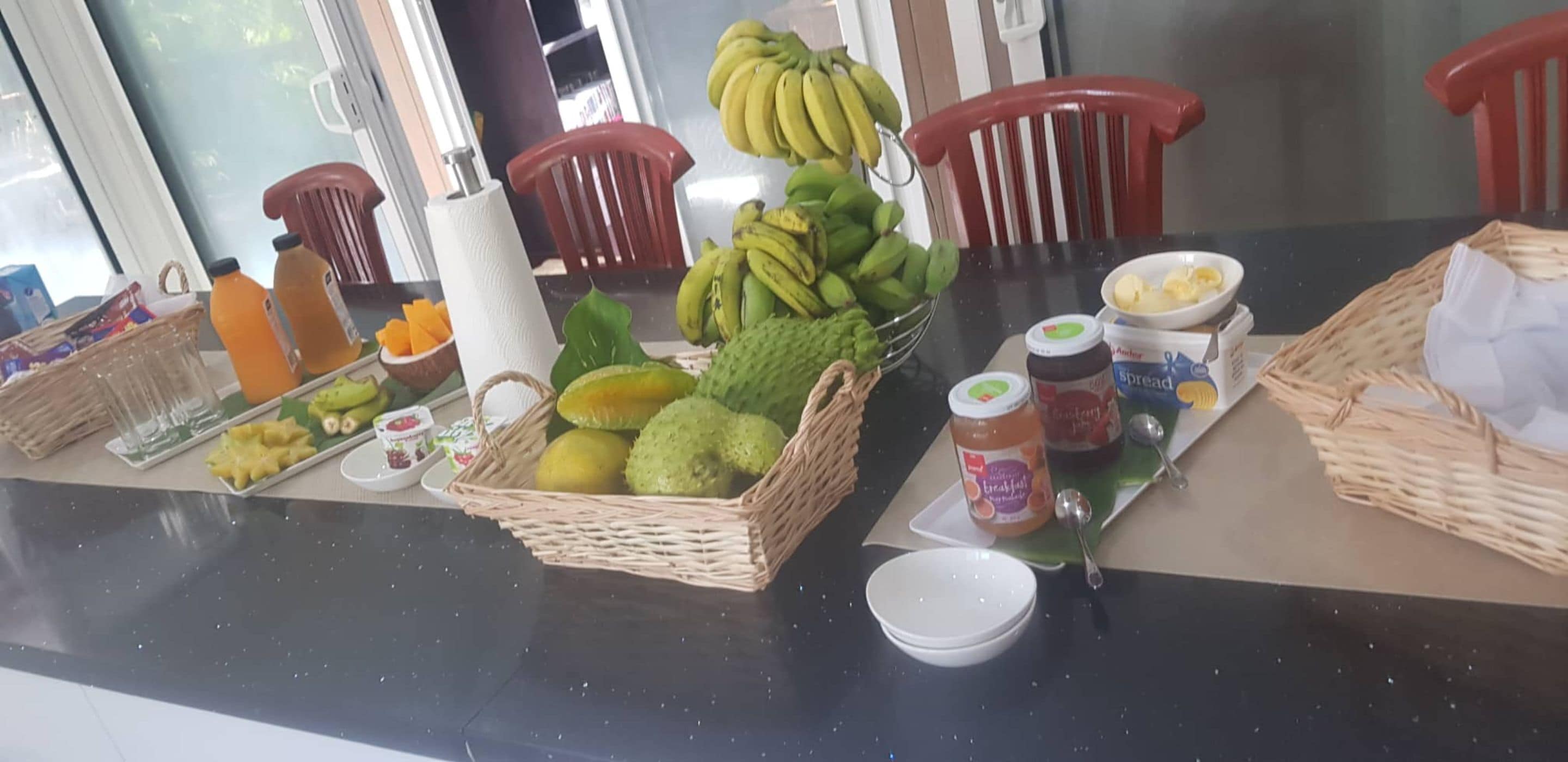 A kitchen counter with various fruits, vegetables, and condiments.