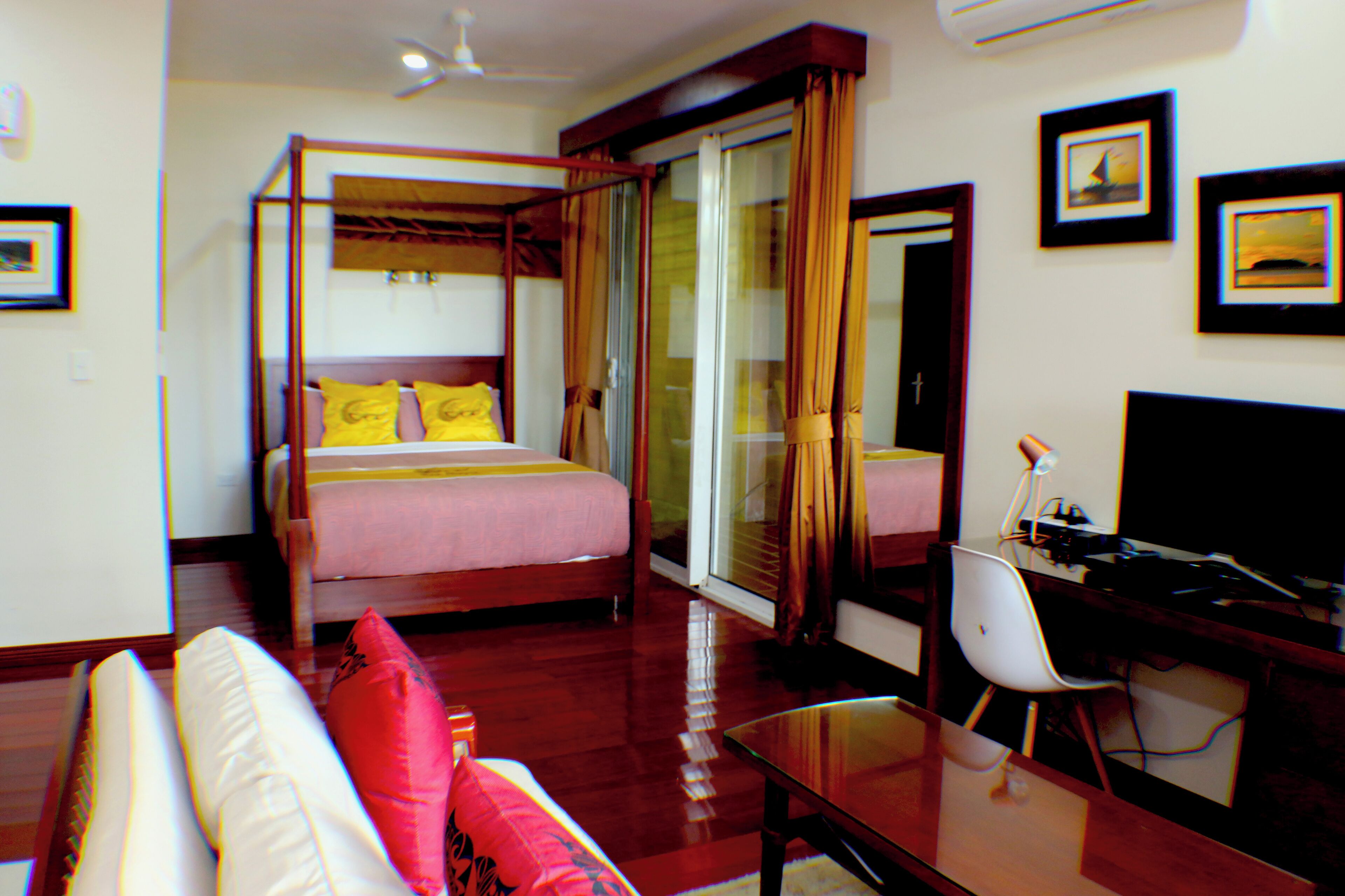 Una habitación de hotel con cama con dosel, un escritorio con silla y un televisor.