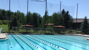 Ein Schwimmbecken mit mehreren Bahnen, umgeben von einem Zaun und Bäumen.